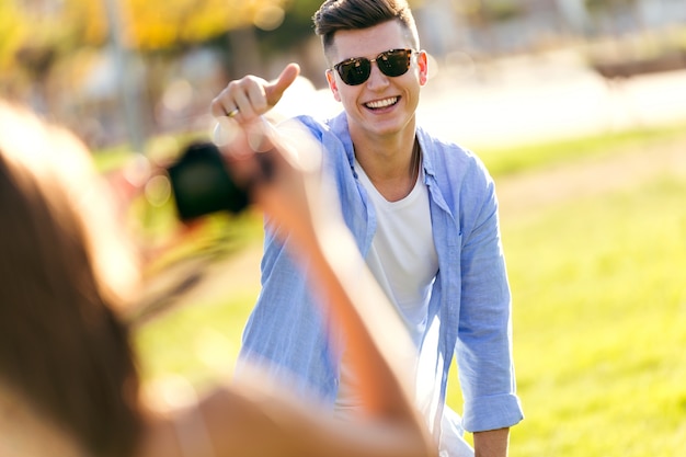 Belle jeune femme prenant la photo de son petit ami dans le parc.