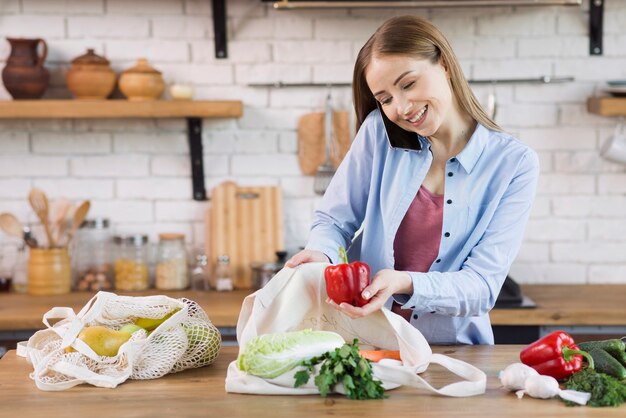 Belle jeune femme prenant des sacs d'épicerie dans des sacs réutilisables