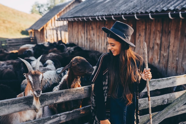 Une belle jeune femme près d'un enclos avec des chèvres