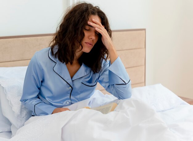 Belle jeune femme en pyjama bleu portant sur le lit