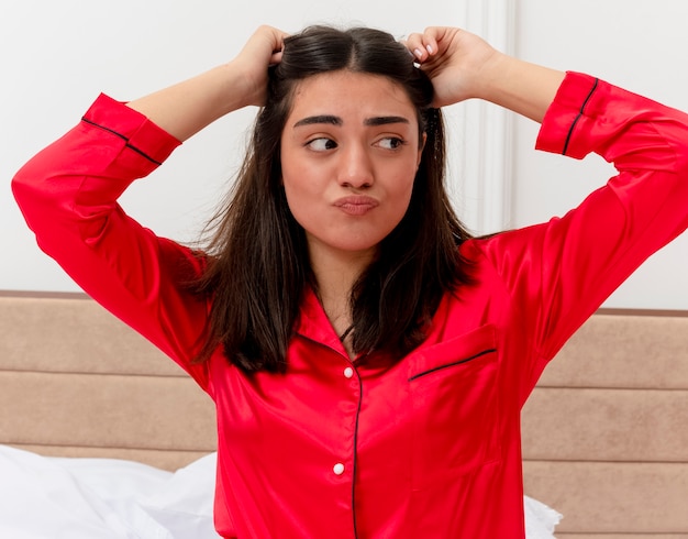 Photo gratuite belle jeune femme en pyjama rouge se détendre dans son lit