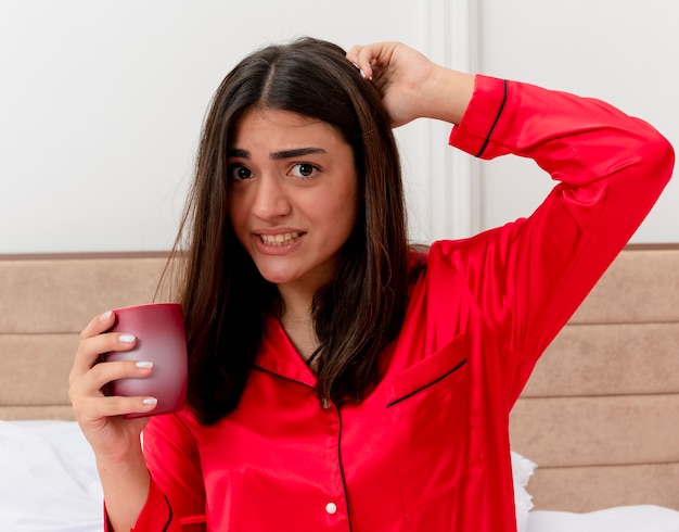 Belle jeune femme en pyjama rouge se détendre dans son lit