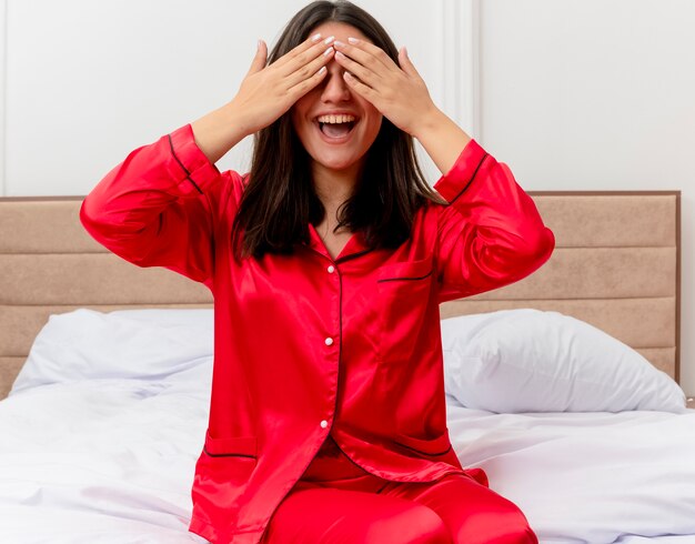 Belle jeune femme en pyjama rouge se détendre dans son lit