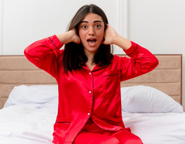 Belle jeune femme en pyjama rouge se détendre dans son lit