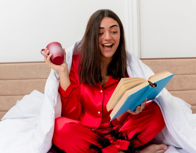 Belle jeune femme en pyjama rouge se détendre dans son lit