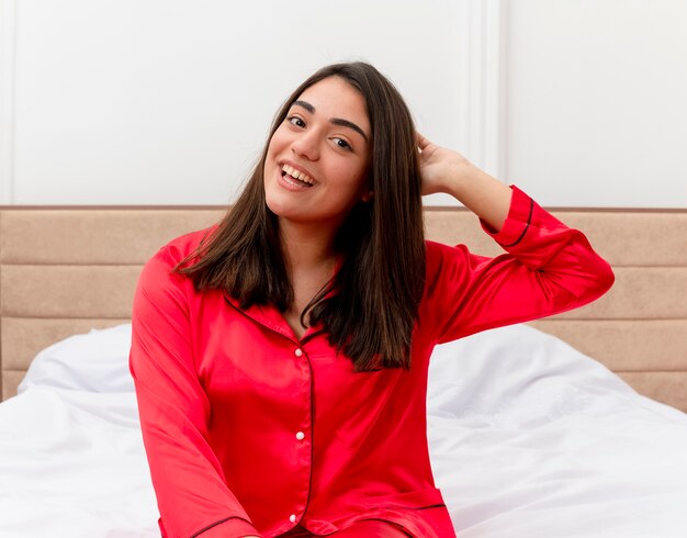 Belle jeune femme en pyjama rouge se détendre dans son lit