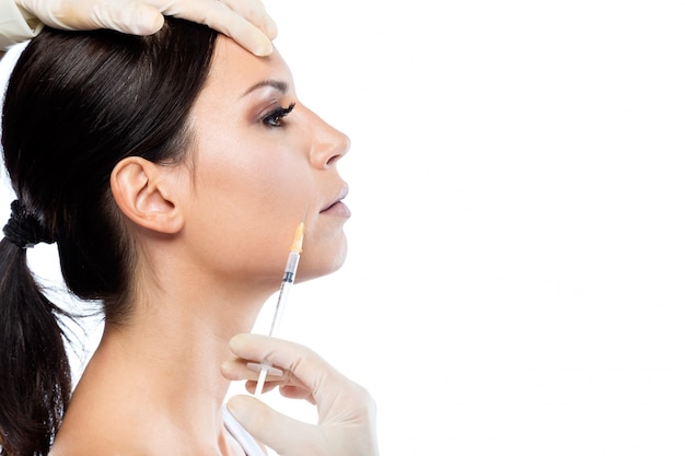 Belle jeune femme recevant une injection cosmétique de botox dans son visage.