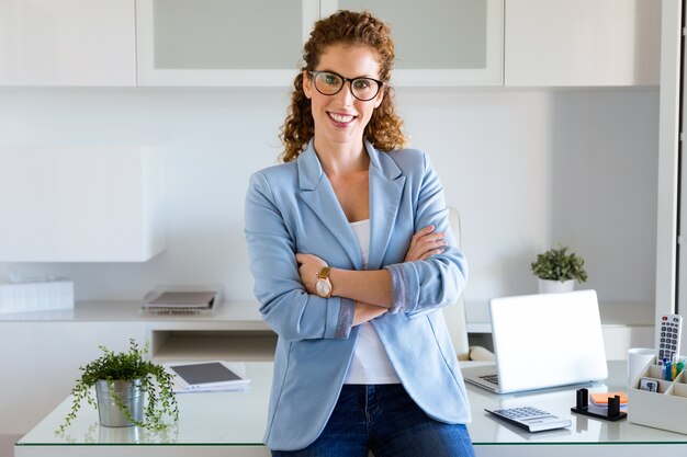 Belle jeune femme regardant la caméra dans le bureau.