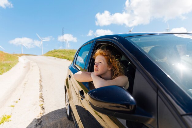 Belle jeune femme regardant par la fenêtre de la voiture