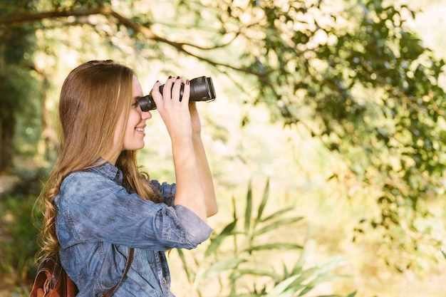 Belle jeune femme regardant à travers les jumelles