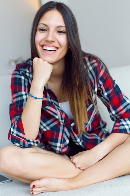 Belle jeune femme regarde la caméra à la maison.