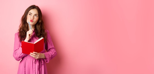 Belle Jeune Femme Regarde L'écriture Réfléchie Dans Un Cahier Tenant Un Planificateur Ou Un Journal Planifie Son Emploi Du Temps