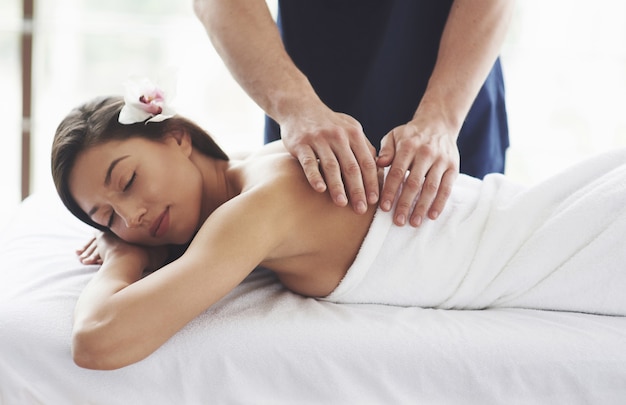 Belle jeune femme relaxante avec massage des mains au spa de beauté.