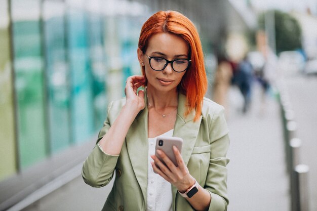 Belle jeune femme réussie en costume vert, parler au téléphone