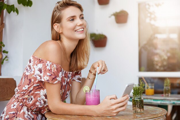 Belle jeune femme en robe au café