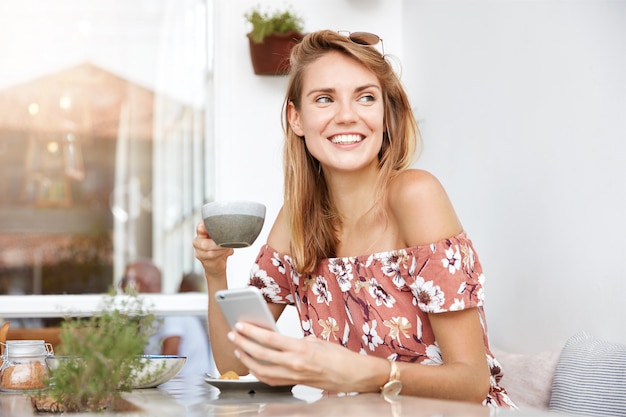 Belle jeune femme en robe au café