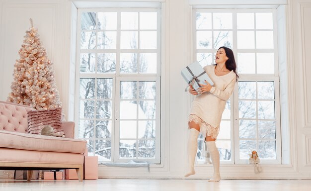 Belle jeune femme en robe blanche posant avec boîte-cadeau