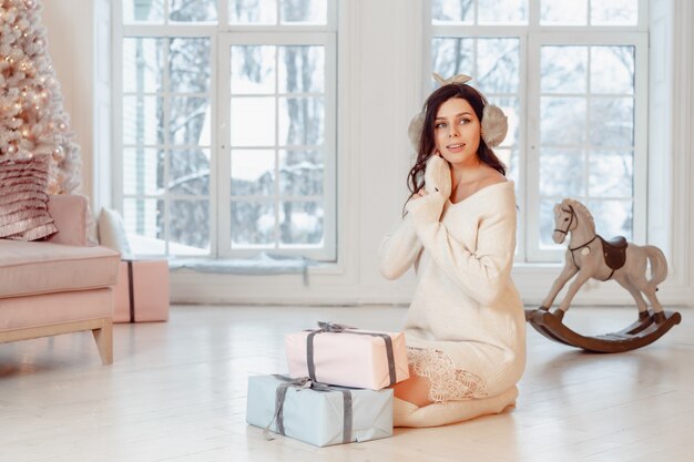 Belle jeune femme en robe blanche posant avec des coffrets cadeaux