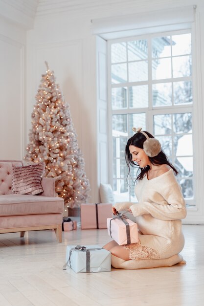 Belle jeune femme en robe blanche posant avec des coffrets cadeaux