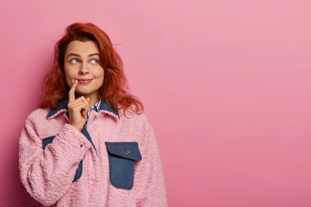 Belle jeune femme rousse naturelle pense à mieux gérer le temps, rêve de quelque chose