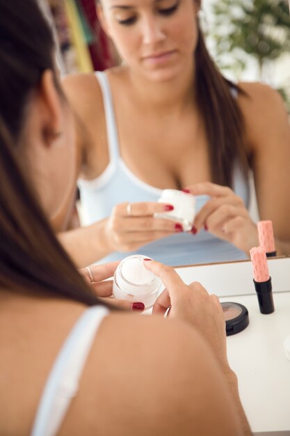 Belle jeune femme s&#39;occupant de sa peau près de miroir dans la salle de bain.