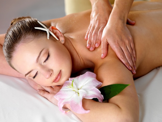 Belle jeune femme se massage relaxant des épaules dans un salon de beauté - à l'intérieur