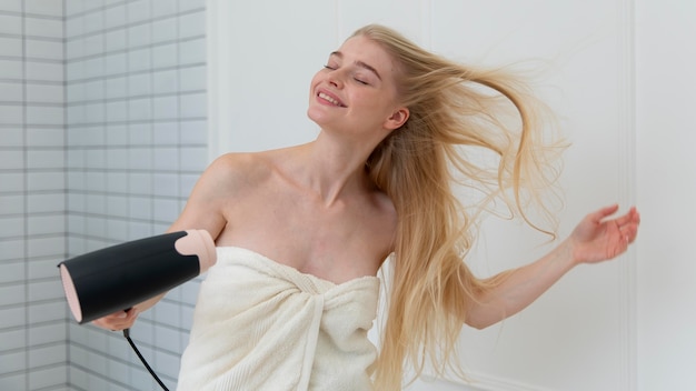 Belle jeune femme séchant ses cheveux