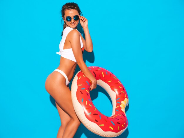 Belle jeune femme sexy souriante à lunettes de soleil. Fille en slip d'été blanc et sujet avec matelas gonflable donut lilo.