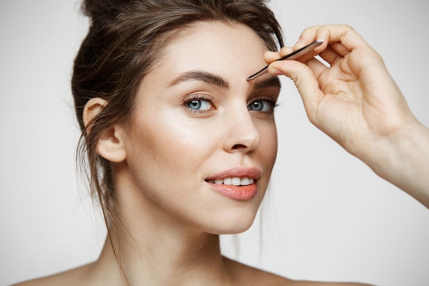 Belle jeune femme avec des sourcils tweeze peau propre parfaite. Traitement facial.