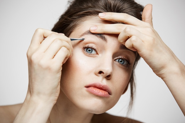 Belle jeune femme avec des sourcils tweeze peau propre parfaite. Traitement facial.