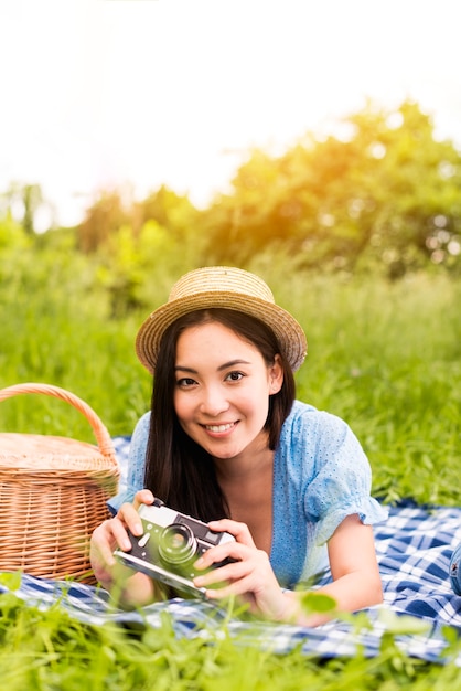 Belle jeune femme souriante avec caméra dans la nature