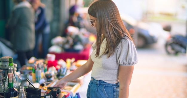 Photo gratuite belle jeune femme souriante heureuse et confiante. debout avec le sourire sur le visage à la recherche d'une brocante à la rue de la ville