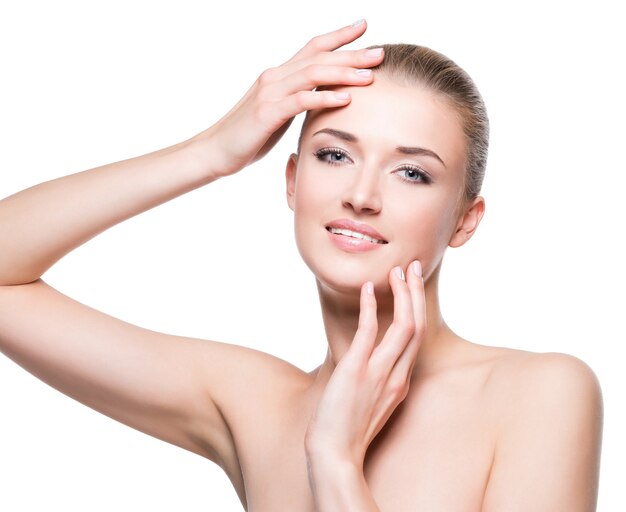 Belle jeune femme souriante heureuse avec une peau propre sur un mur blanc.