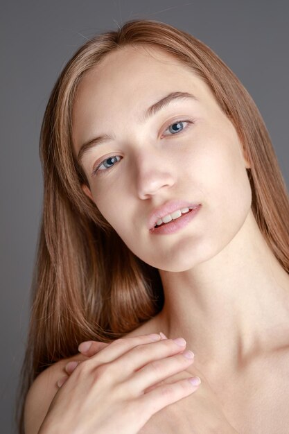 Belle jeune femme souriante avec une peau parfaite visage beauté naturelle concept isolé sur fond gris studio