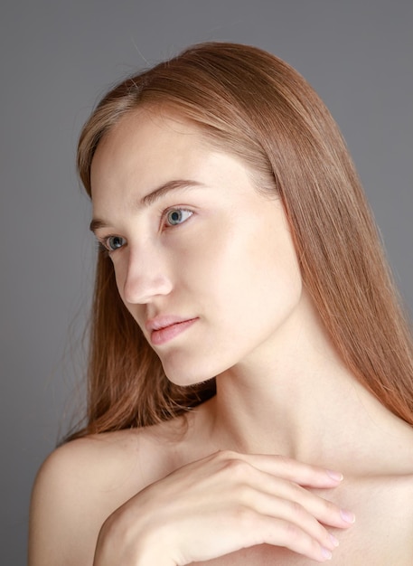 Belle jeune femme souriante avec une peau parfaite visage beauté naturelle concept isolé sur fond gris studio