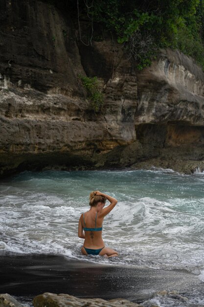 Belle jeune femme svelte aux longs cheveux blonds en maillot de bain sur la plage près de l'océan. Se relaxer sur la plage. Vacances tropicales.