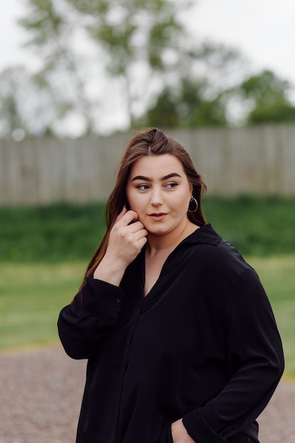 Belle jeune femme sympathique aux cheveux bruns longueur épaule posant à l'extérieur