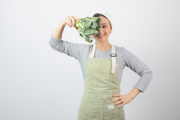 Photo gratuite belle jeune femme en tablier posant avec du brocoli frais sur blanc