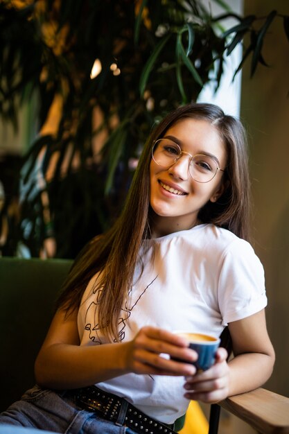 Belle jeune femme avec une tasse de café dans un café