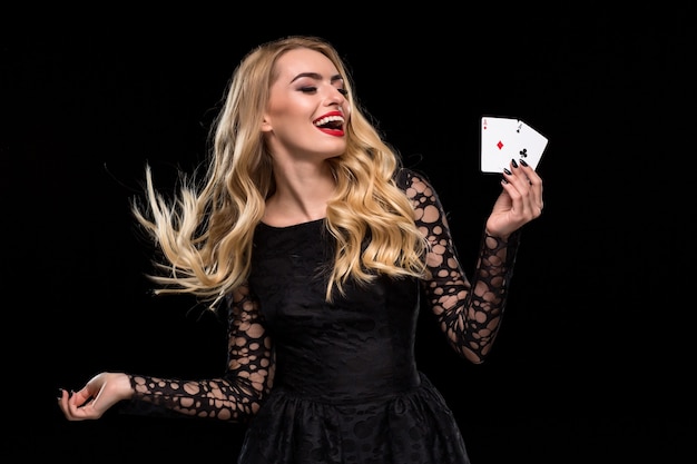 Belle jeune femme tenant deux as de cartes dans sa main isolé sur fond noir