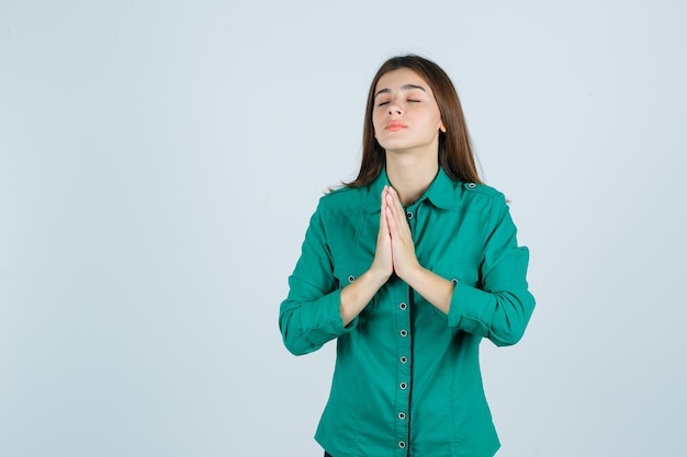 Belle Jeune Femme Tenant Par La Main En Signe De Prière En Chemise Verte Et à La Recherche D'espoir, Vue De Face.