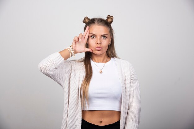 Belle jeune femme en tenue blanche posant à la caméra.