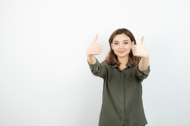 Belle jeune femme en tenue décontractée debout et donnant les pouces vers le haut. Photo de haute qualité