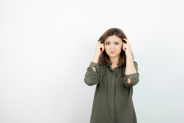 Belle jeune femme en tenue décontractée debout sur un mur blanc. Photo de haute qualité