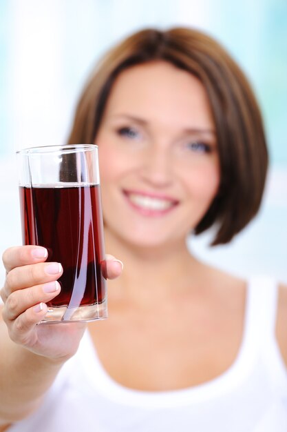 belle jeune femme tient un verre de jus de cerise