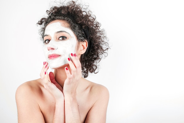 Belle jeune femme touchant son masque isolé sur fond blanc