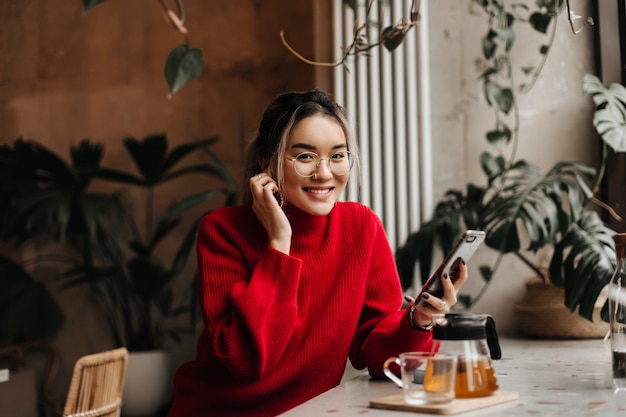 Photo gratuite belle jeune femme touche sa boucle d'oreille et regarde devant avec le sourire