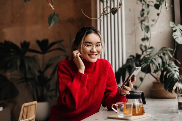 Belle jeune femme touche sa boucle d'oreille et regarde devant avec le sourire