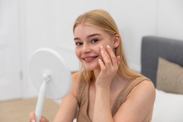 Belle jeune femme utilisant un produit de soin du visage