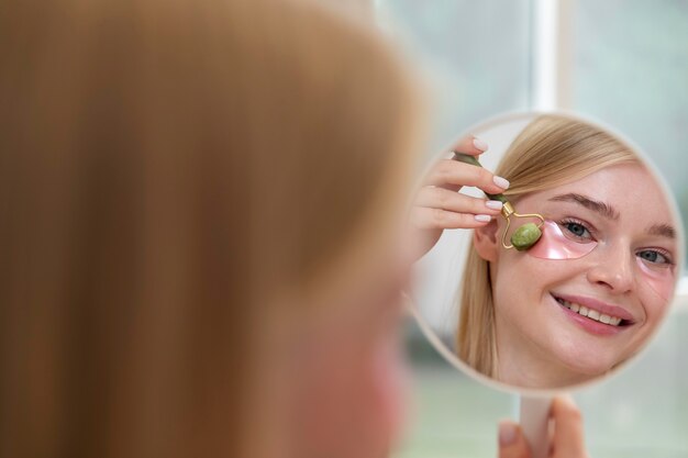 Belle jeune femme utilisant un produit de soin du visage